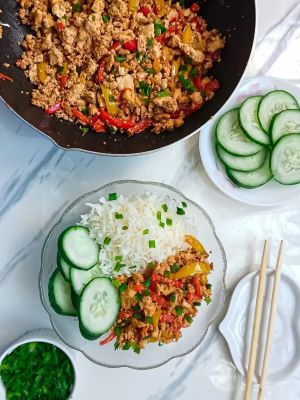 A bowl of chili garlic tofu scramble with rice and cucumbers.  The cooked dish of Chili Garlic Tofu Scramble and a bowl of cucumbers on the side.  