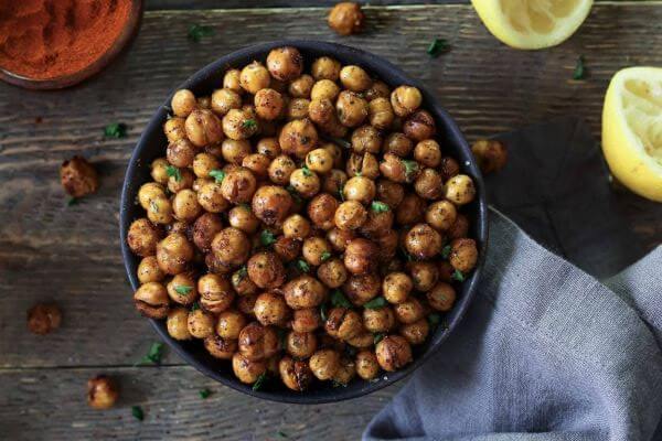 A bowl of air fried chickpeas with Lemon wedges on the side