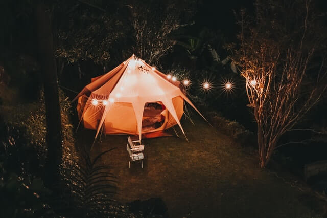 A night time picture of A lit up Yurt with String lights outside